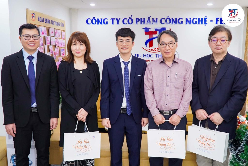 Ông Lê Văn Toản (ở giữa) cùng Thầy Nguyễn Văn Tư (ngoài cùng bên trái) đại diện trung tâm trao quà lưu niệm cho đại diện Trường Đại Học Catholic